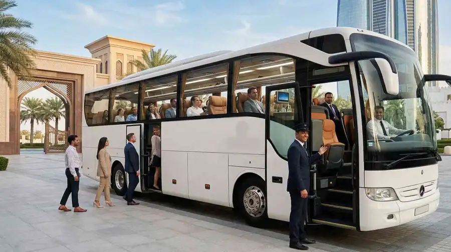 A modern white Mercedes luxury coach is parked near the Sheikh Zayed Grand Mosque, showcasing one of the Best Luxury Bus Rental Services in Abu Dhabi with elegant branding and passengers boarding.