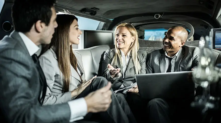 Business team conversing inside luxury limousine in Abu Dhabi.