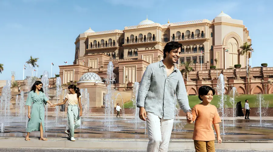 Family walking together near the water fountains in front of the iconic Emirates Palace in Abu Dhabi.